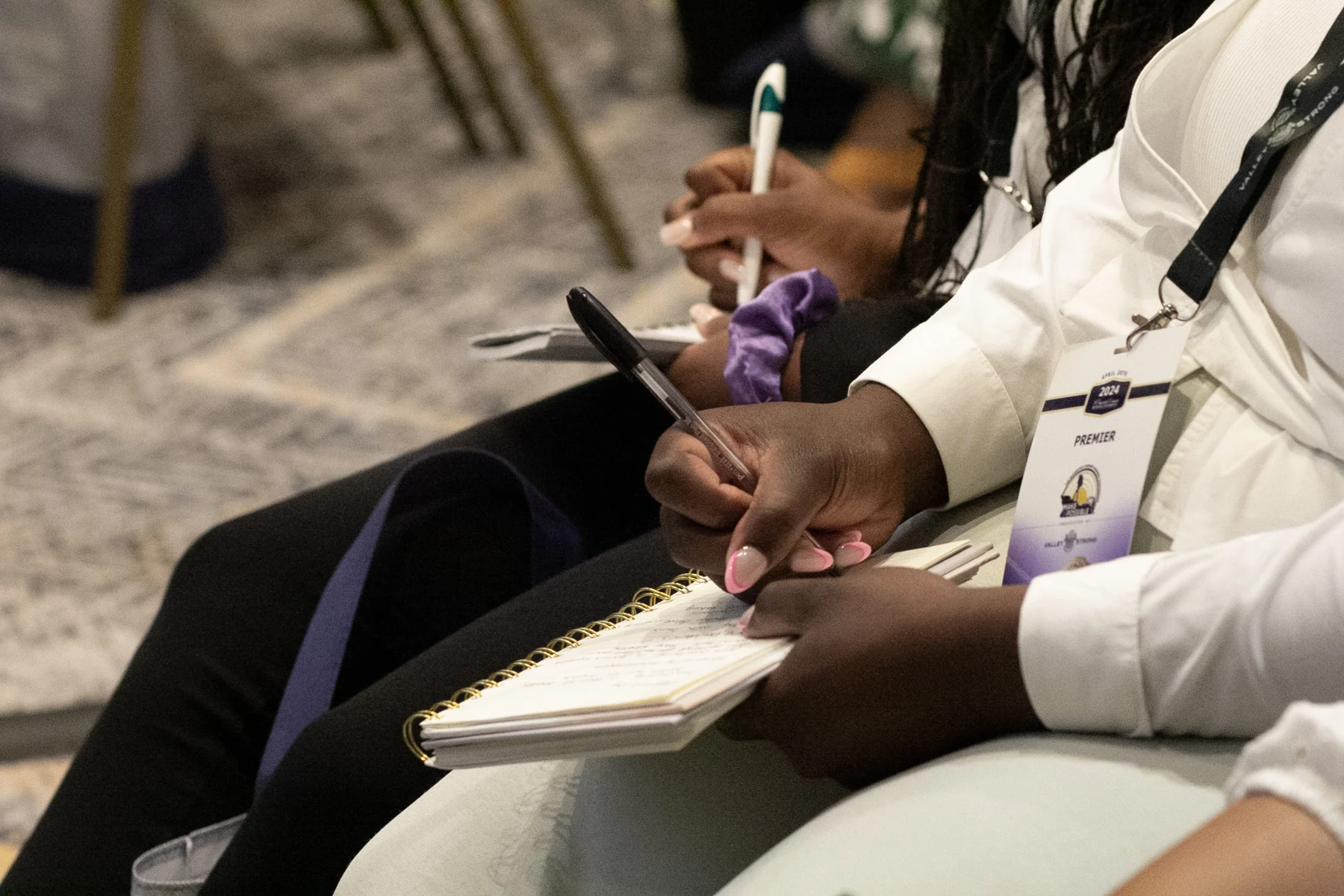 A conference participant writing notes during a learning session